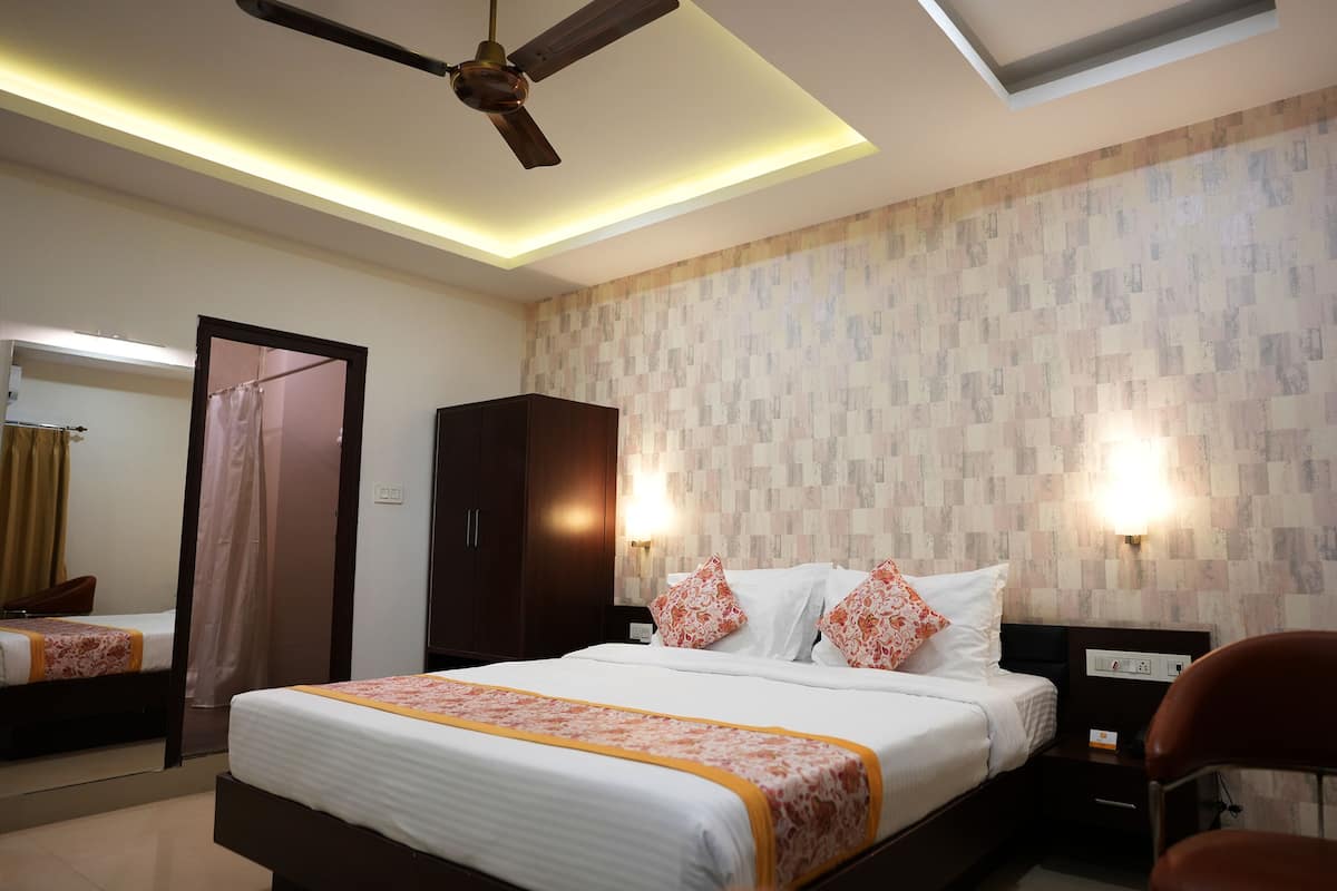 Una habitación de hotel con cama, mesitas de noche, armario, ventilador de techo y espejo.