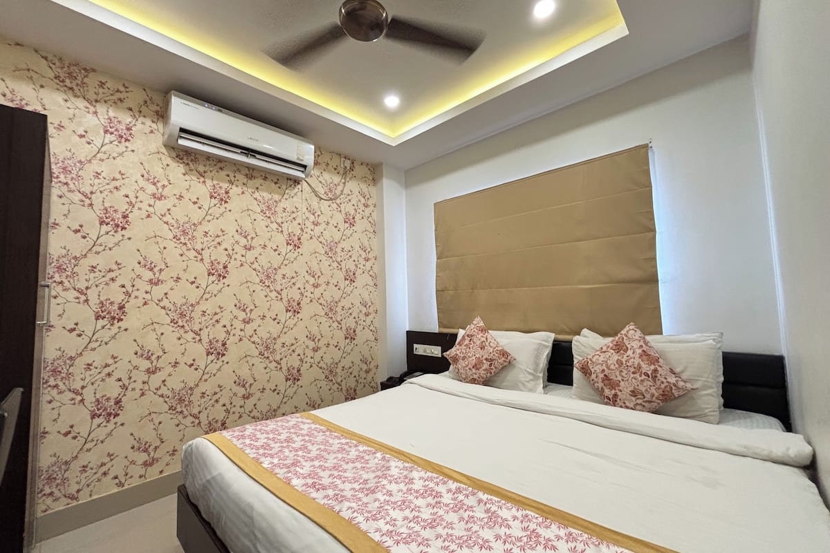 Un dormitorio con cama, aire acondicionado, ventilador de techo y papel tapiz floral.