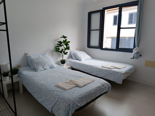 A bedroom with two beds, a potted plant, a window, and a lamp. - Villa-costaadeje-3br-balcony-wifi-parking (Adeje)