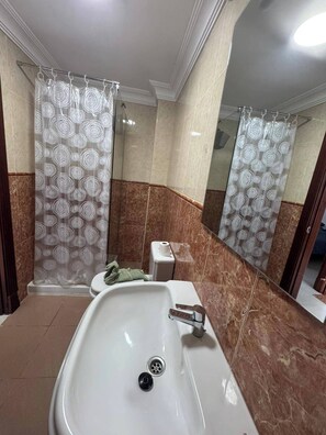 Un baño con un lavamanos blanco, un inodoro y una cortina de ducha con diseño circular.