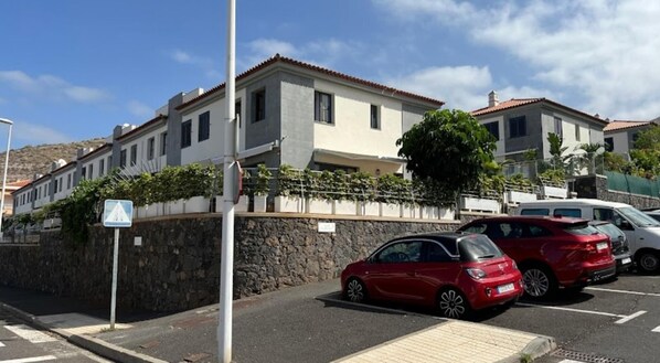 A row of modern two-story houses with a stone wall and a paved parking area.