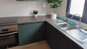 Een moderne keuken met donkergroene kastjes, een roestvrijstalen spoelbak en een potplant.