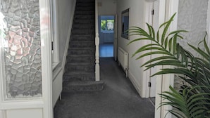 A hallway with a stone wall, a staircase, and a plant. - Cosy Bee  (Bournemouth)
