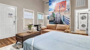 A bedroom with a bed, a sofa, a dresser, and a large window. - Water Street Hideaway (Wilmington)
