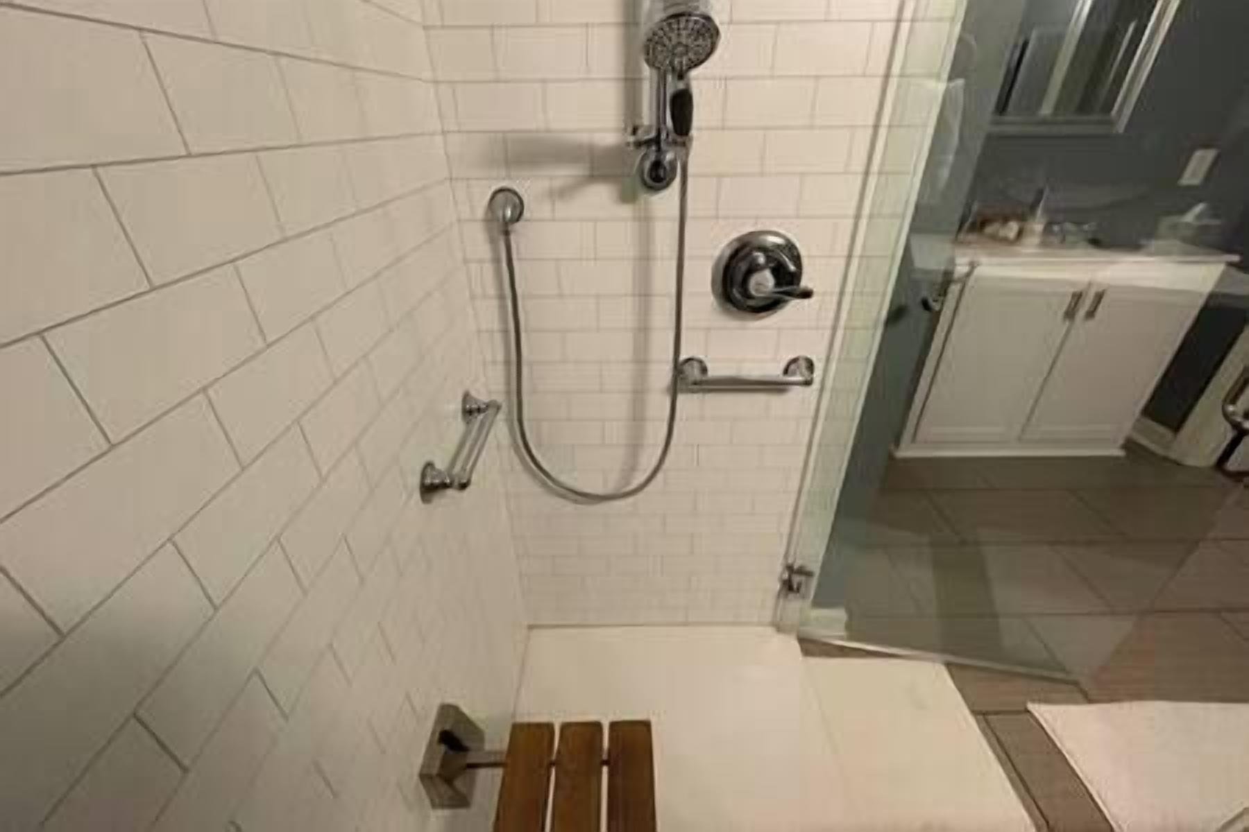 Una doccia con soffione manuale e doccetta, un portascopevoli e una porta doccia in vetro.