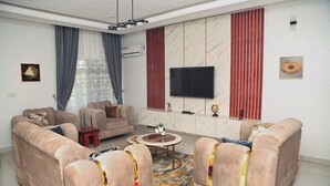 A modern living room with two sofas, a coffee table, and a TV mounted on the wall. - Lushville Hotel and Suites  (Benin City)