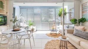 Un salon moderne avec une table à manger ronde, des chaises blanches, un canapé et un téléviseur.