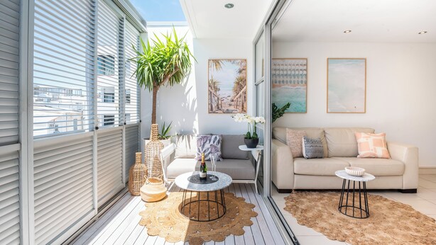 Un balcon moderne avec un canapé, une petite table ronde et une plante en pot.