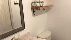 Ein Badezimmer mit einem großen Spiegel, einem Waschbecken mit Marmorplatte und zwei Regalen mit Handtüchern und einem Korb.