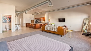 Ein geräumiger Wohnbereich mit einem großen Bett, einer Couch und einer Küche im Hintergrund.
