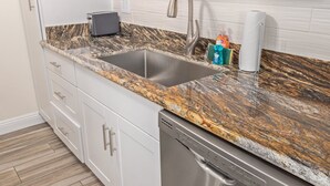 Cuina amb taulell de granit, rentaplat i vàter d'acer inoxidable.