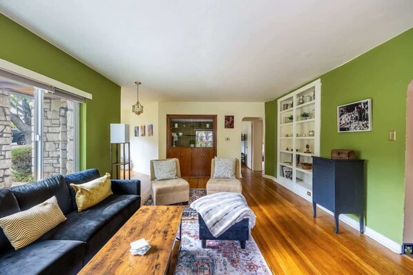 Una sala de estar con un sofá, sillones, una mesita de centro y una estantería.