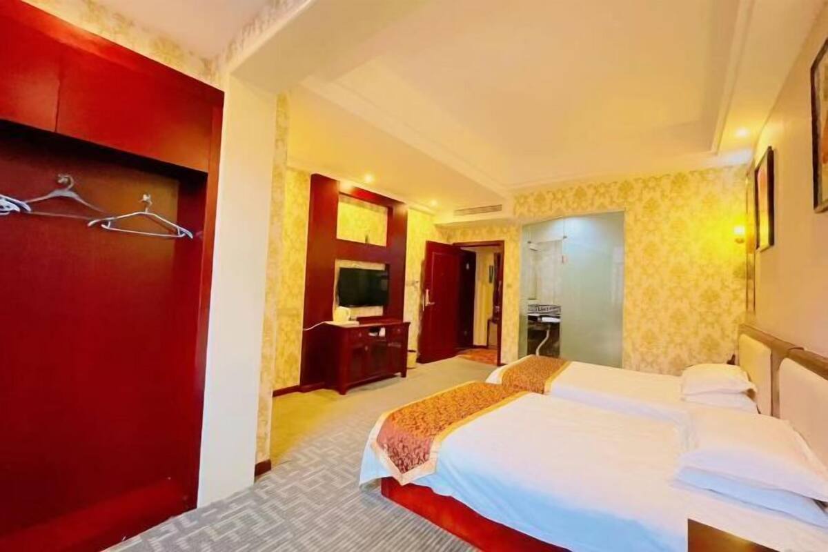 A hotel room with two beds, a desk, a television, and a wardrobe.