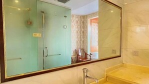 Un baño con un espejo grande, un lavabo y una ducha con cerramiento de vidrio.