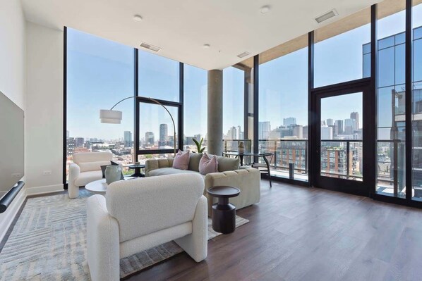 Amplia sala de estar con ventanas grandes, vistas a la ciudad y muebles modernos.