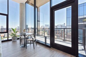Un apartamento alto con amplios ventanales que ofrecen vista a la ciudad, una mesa de comedor redonda y una planta en maceta.