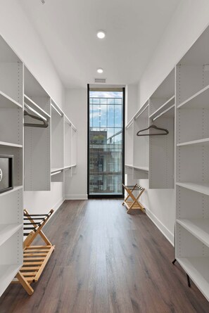 A modern, empty walk-in closet with white shelving and wooden drying racks.