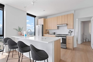 A modern kitchen with a central island, stainless steel appliances, and wooden cabinets.
