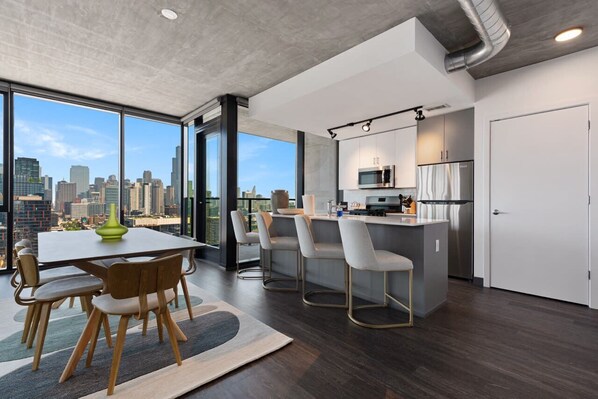 A modern kitchen with a city view, a dining area with a table and chairs, and a large window.