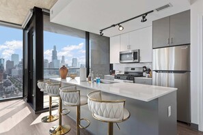 Una cocina moderna con una isla grande, electrodomésticos de acero inoxidable y vistas a la ciudad.
