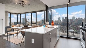 Una cocina moderna con una isla grande, un comedor con vista a la ciudad y un balcón con mobiliario exterior.