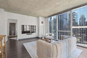 A modern living room with a large window, a sofa, a TV, and a chair.