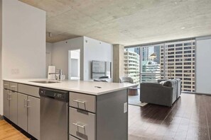 A modern kitchen with a dishwasher, a large island, and a dining area with a sofa.
