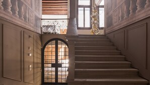 Una àmplia escala amb un paviment a escacs que condueix a un balcó amb vista al pati.