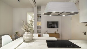 Een moderne keuken met een marmeren aanrecht, een inbouwfornuis en een grote hanglamp.