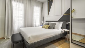 Een moderne slaapkamer met een groot bed, een nachtkastje, een stoel en een spiegel.