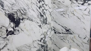 Une salle de bain avec un mur en marbre et un lavabo.