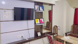 Une chambre d’hôtel dotée d’un grand miroir, d’un téléviseur à écran plat, d’un bureau en bois et de deux chaises.