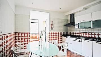 A compact kitchen with white cabinets, a black range hood, and a tiled backsplash.