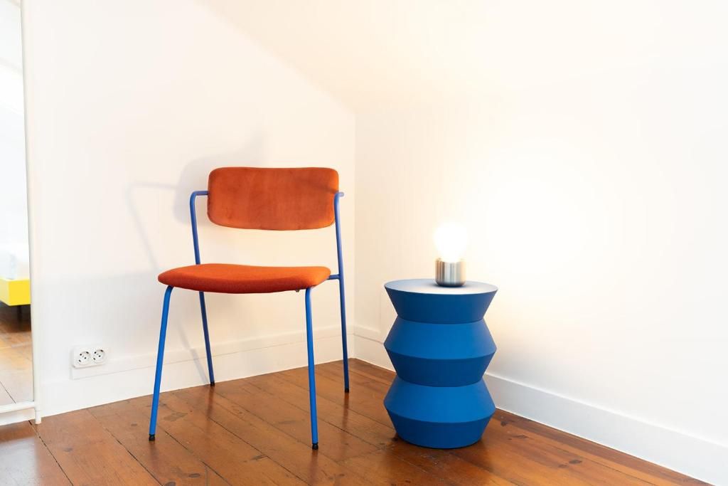 A chair with a cushion and a blue base, positioned next to a wall socket.