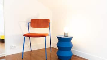 A chair with a cushion and a blue base, positioned next to a wall socket.