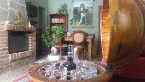 Ein gemütliches Wohnzimmer mit Kamin, Bücherregal, Globus und einem Tisch mit Gläsern und Flaschen.