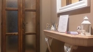 Ein Badezimmer mit Holztür, einem Spiegel über einem Waschtisch und einem Fliesenboden.