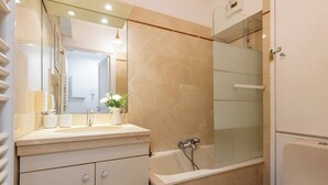 A bathroom with a bathtub, a glass-enclosed shower, and a vanity with a mirror. - Geranimus Versailles Charost (Versailles)