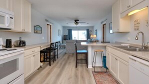 Una cucina moderna con mobili bianchi, un'isola centrale e un'area pranzo con sedie.