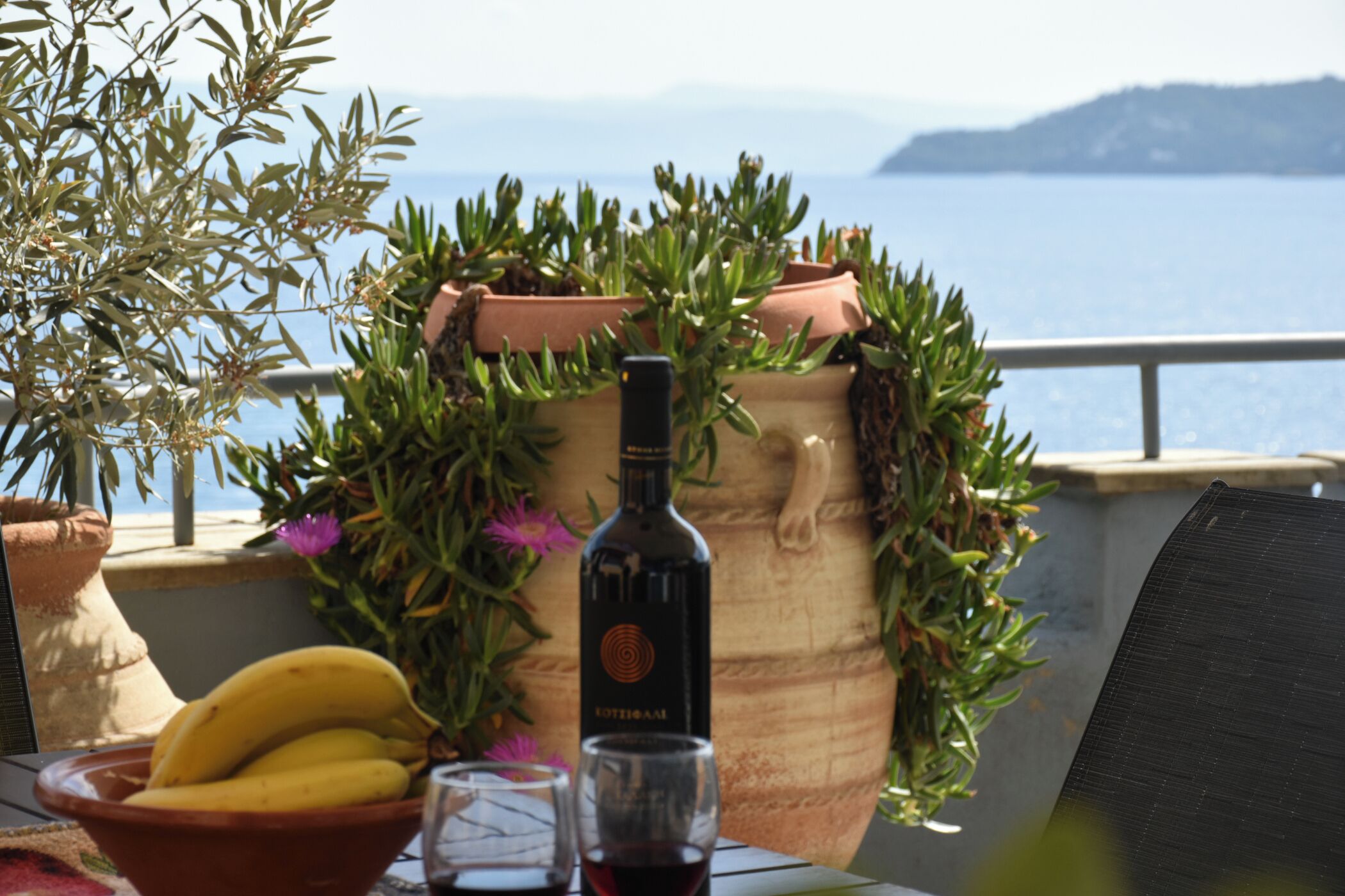 Une table avec une bouteille de vin, un verre et un bol de bananes.