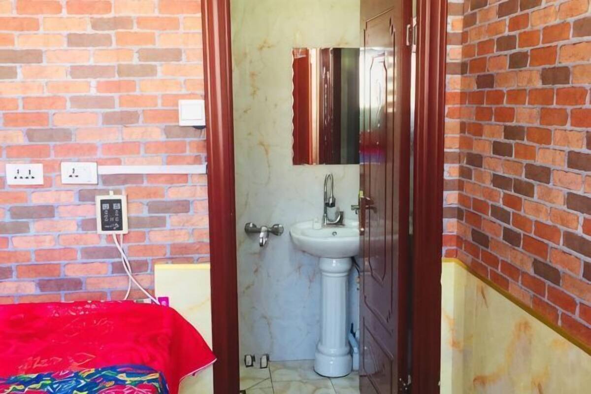 A bathroom with a white sink, a mirror, and a red towel on the floor.