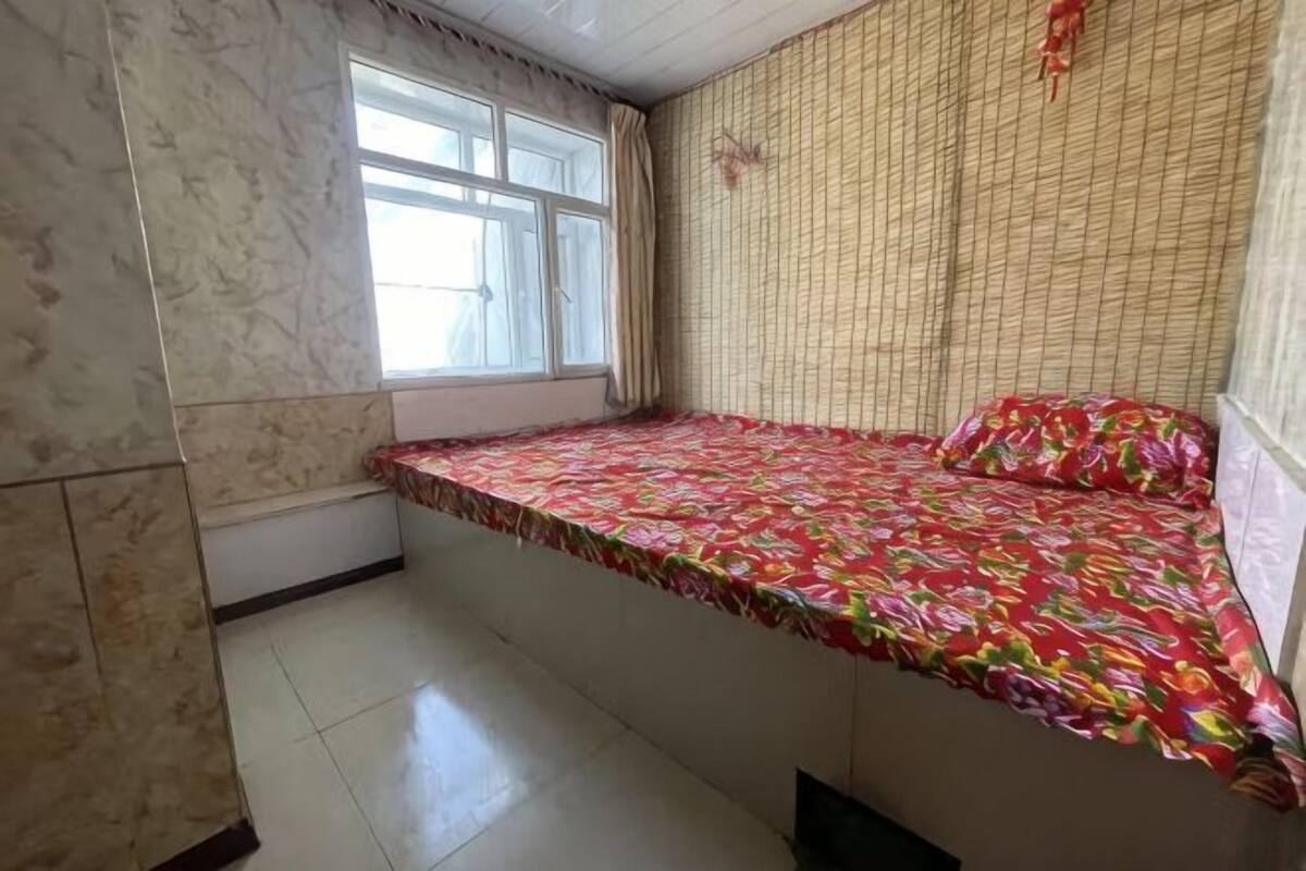 A room with a bed, a window, and a tiled floor.
