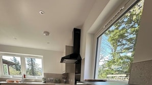 Una cocina moderna con un ventanal grande, suelo de madera y horno empotrado.