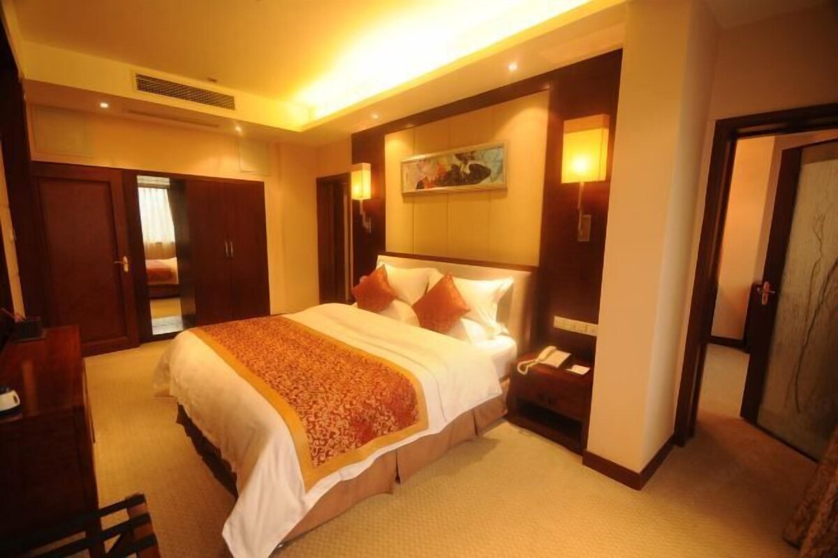 Una habitación de hotel con una cama grande, una mesita de noche y un cuadro en la pared.