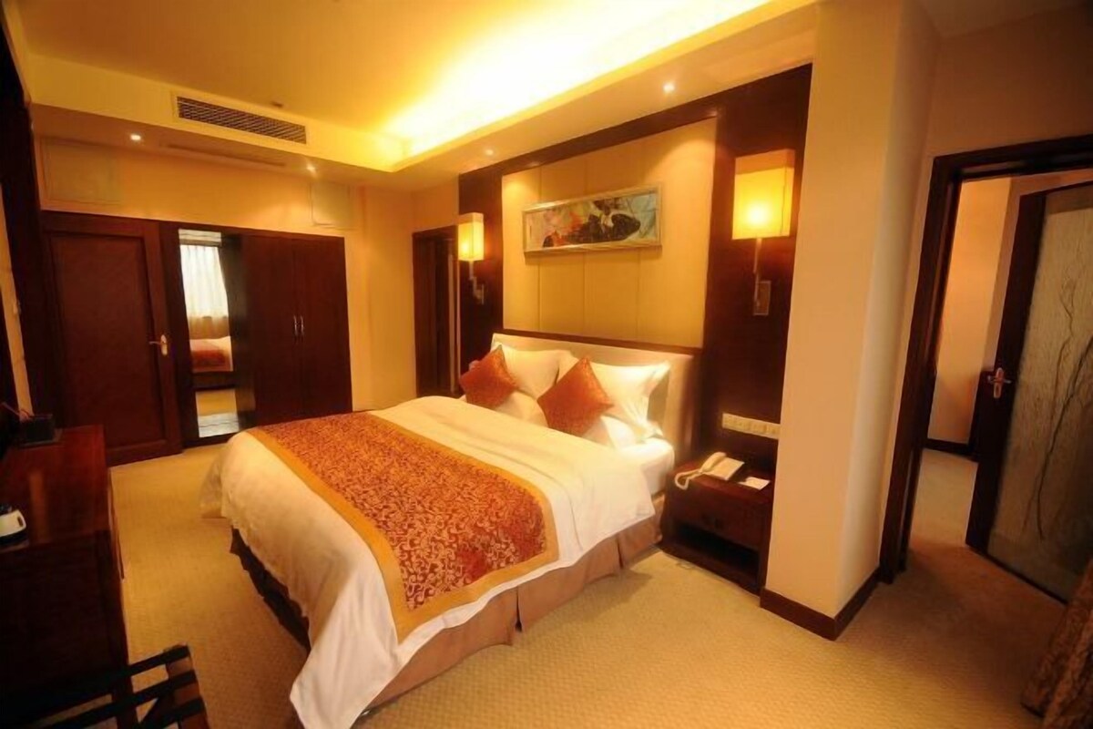 Habitación de hotel con una cama grande, un escritorio, una silla, una mesita de noche y un cuadro en la pared.