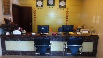 A reception desk with two chairs, a computer, and a counter with various items.