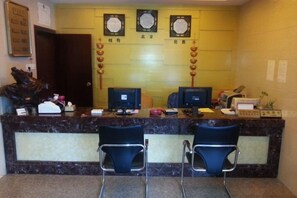 A reception desk with two chairs, a computer, and a counter with various items. - Changting Peace Hotel (Changting)