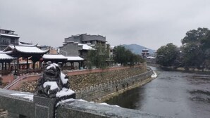 A traditional building with a stone wall and a river in the background. - Changting Peace Hotel (Changting)