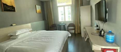 A hotel room with a bed, a desk, a chair, a television, and a window with curtains.