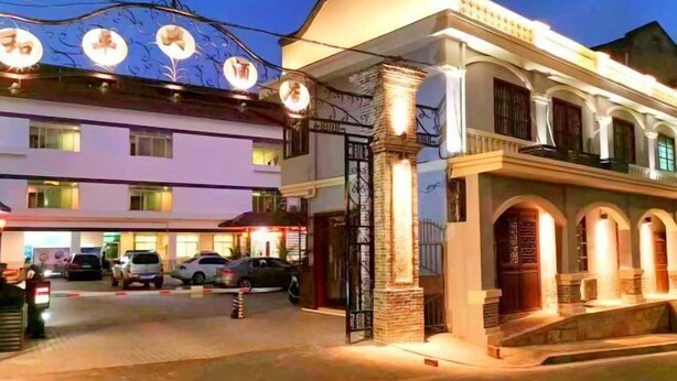 A hotel with a traditional architectural style, featuring arched windows and a well-lit entrance. - Changting Peace Hotel (Changting)